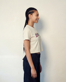 Person wearing a white t-shirt with colorful text and dark pants against a plain background. Extremely Gifted cropped cotton shirt with abstract graphic design, relaxed fit with dropped shoulders and shorter length LOVEUS