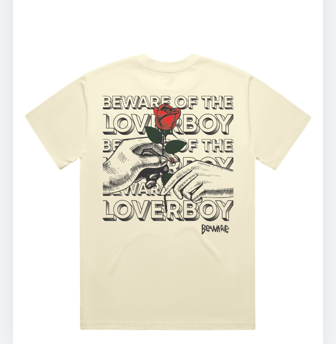 The back view of the beige Beware of the Loverboy Heavyweight Tee displayed flat on a white background, highlighting the large statement rose graphic.
