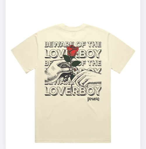 The back view of the beige Beware of the Loverboy Heavyweight Tee displayed flat on a white background, highlighting the large statement rose graphic.