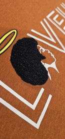 A detailed close-up shot of the Caramel Angel tee, highlighting the intricate, raised embroidered textures that beautifully mimic natural hair.