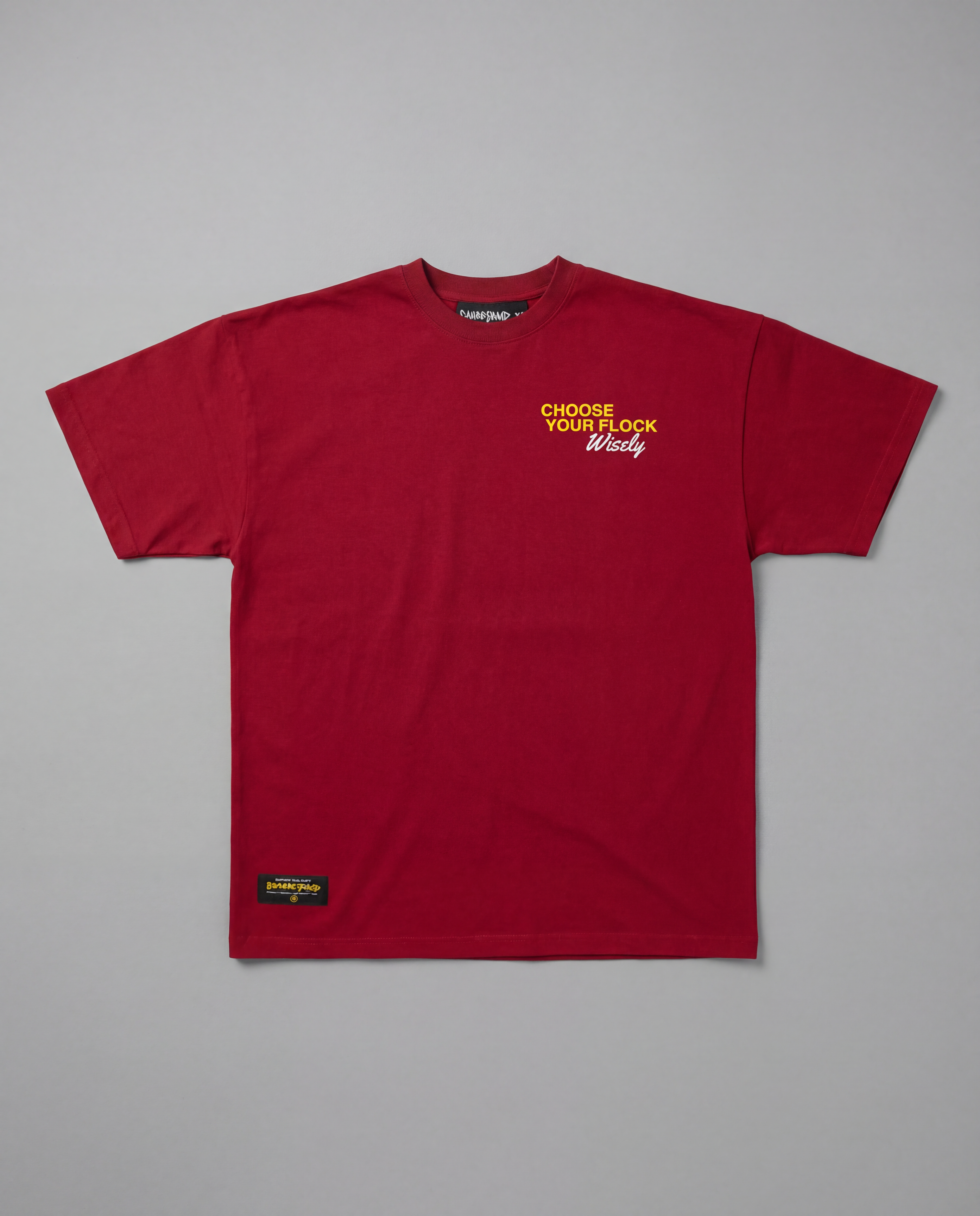 Flat lay front view of the maroon Choose Your Flock Heavyweight Graphic Tee against a gray studio background, highlighting the bold yellow text printed on the chest.