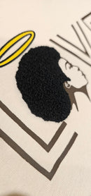 A detailed close-up of the Ivory Angel cotton shirt showcasing the intricate, raised embroidered afro design mimicking natural hair texture.